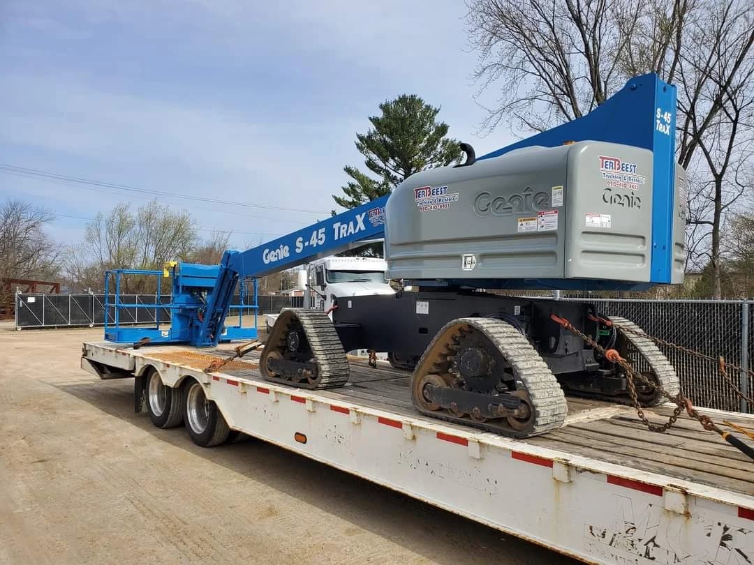 A TerBeest tracked boom lift loaded on an equipment trailer